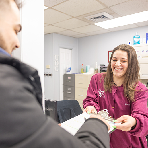 Dental team member taking clipboard from patient