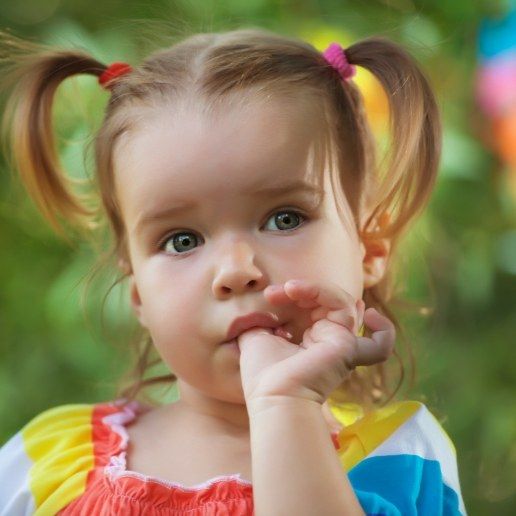 Toddler girl with pigtails sucking her thumb