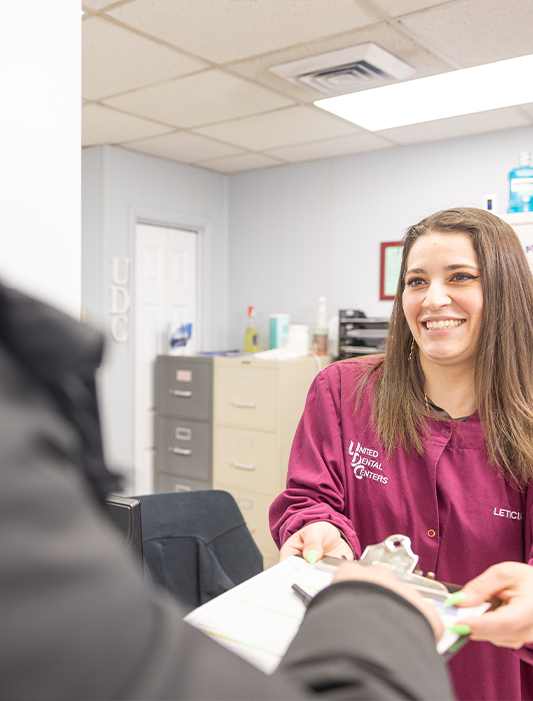 Dental team member in Whiting handing clipboard to patient