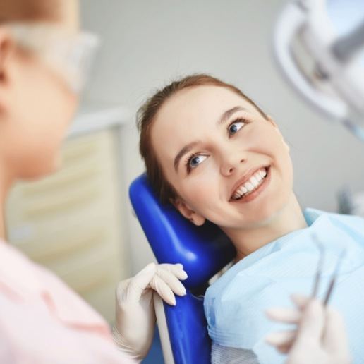 Young woman in dental chair smiling at her cosmetic dentist