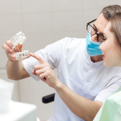 Dentist showing a dental implant model to a patient