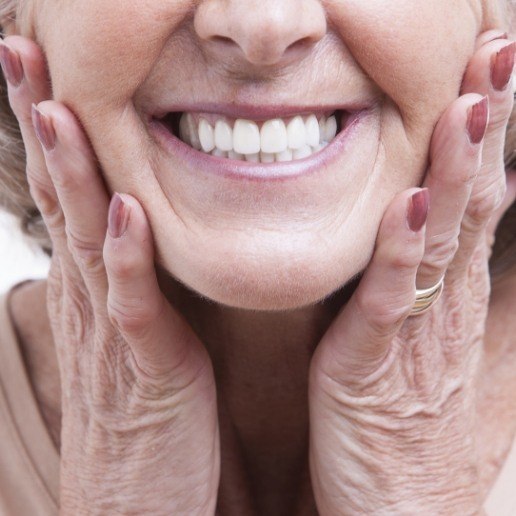 Senior woman grinning and touching her face