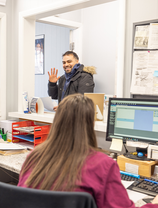 Man waving at dental team member who is maximizing dental insurance in Whiting