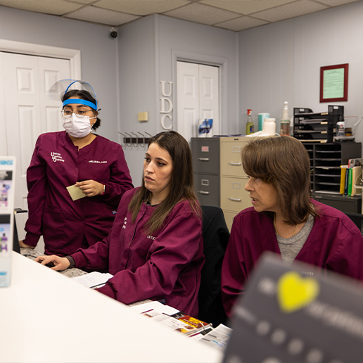 Three dental team members sitting behind front desk