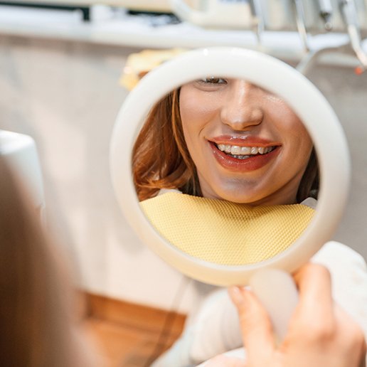 Patient with clear aligners smiling at reflection in mirror