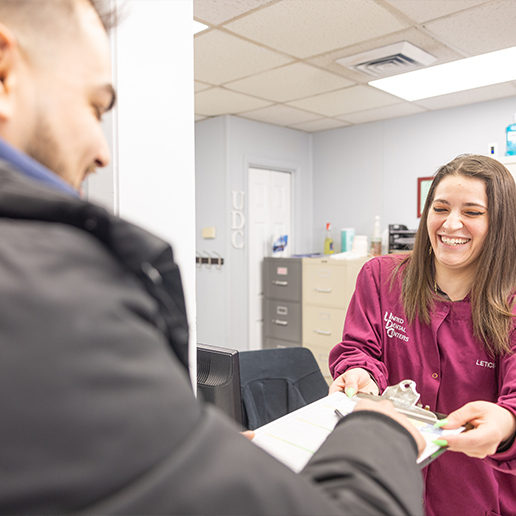 Dental team member taking a clipboard from a patient