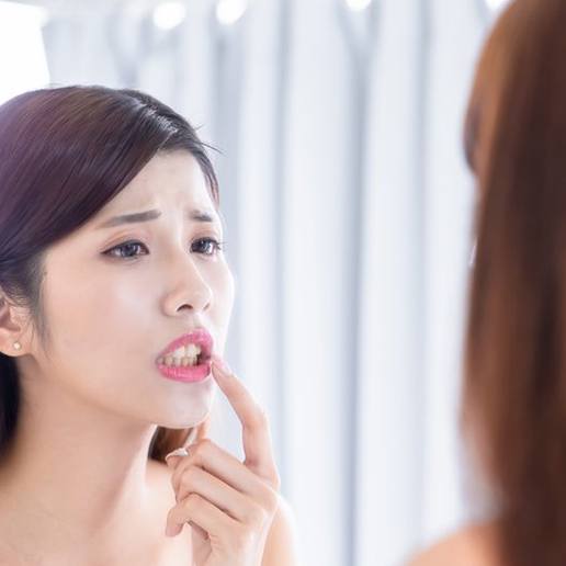 Woman examining her gummy smile in mirror