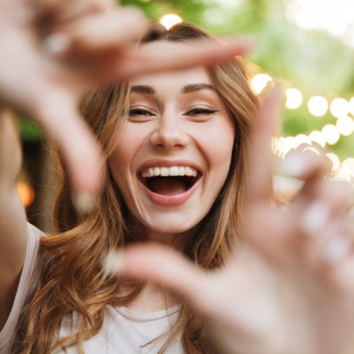 Woman using her fingers to frame her smile 