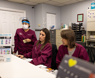 Three dental team members sitting behind dental office front desk