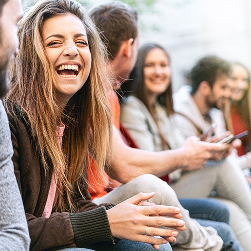 Whiting patient laughing with friends at park after cosmetic dentistry