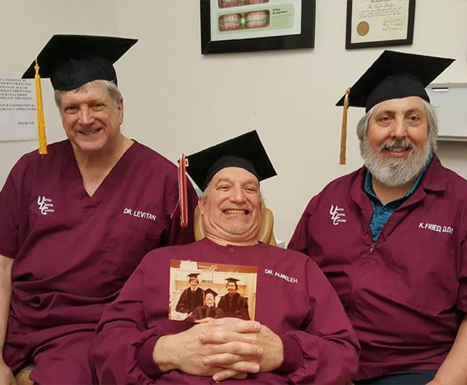 Three Whiting dentists wearing graduation caps and holding a photo of them graduating from dental school