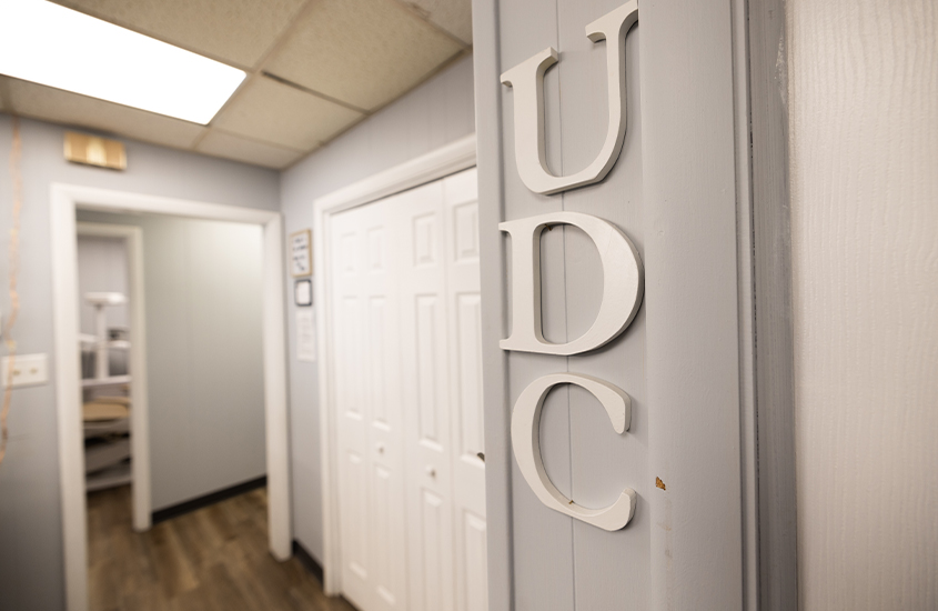 The letters U D C on the wall of dental office hallway