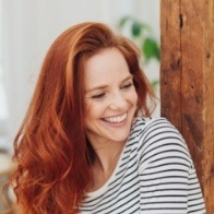 Woman with red hair and striped blouse grinning