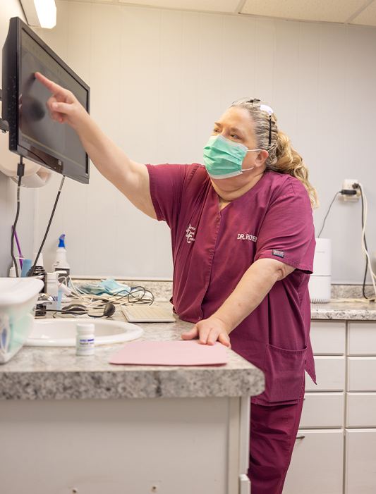 Dentist pointing to computer screen during appointment for restorative dentistry in Whiting