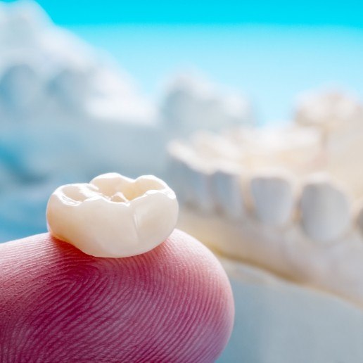 Person holding a dental crown on their finger