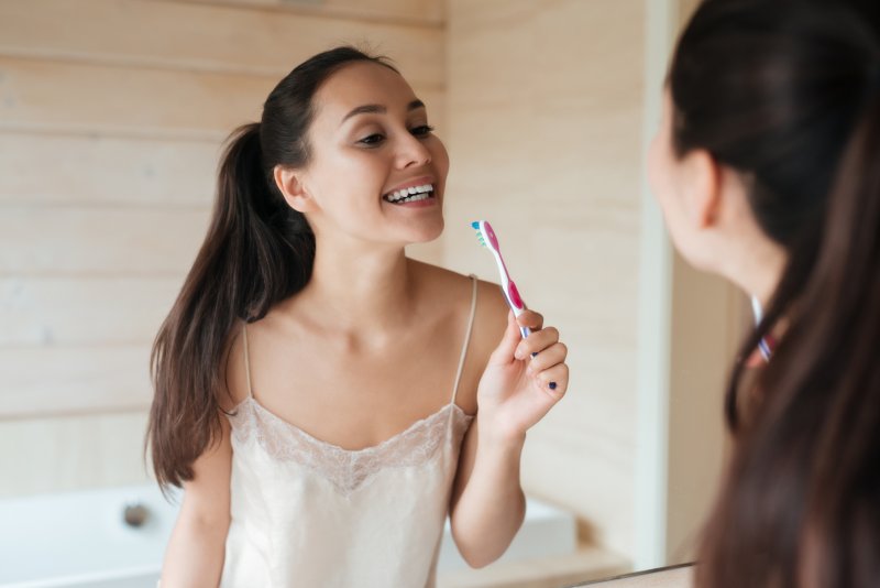 Woman smiling in the mirror holding a toothbrush