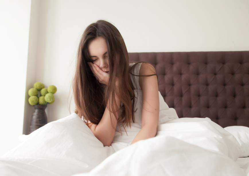 Woman in bed holding jaw