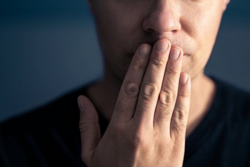 An embarrassed man hiding his smile with his hand